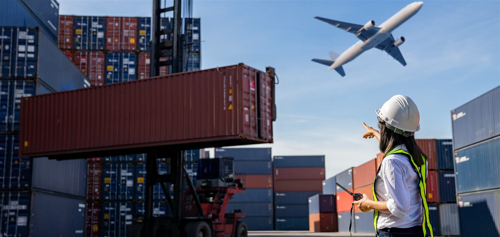 Especialista de comercio exterior supervisando la carga aérea y terrestre en una terminal de contenedores